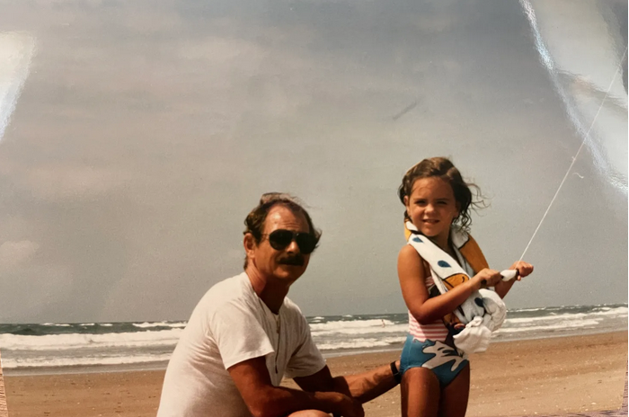 Happy father and seven year old daughter fishing on sunny beach